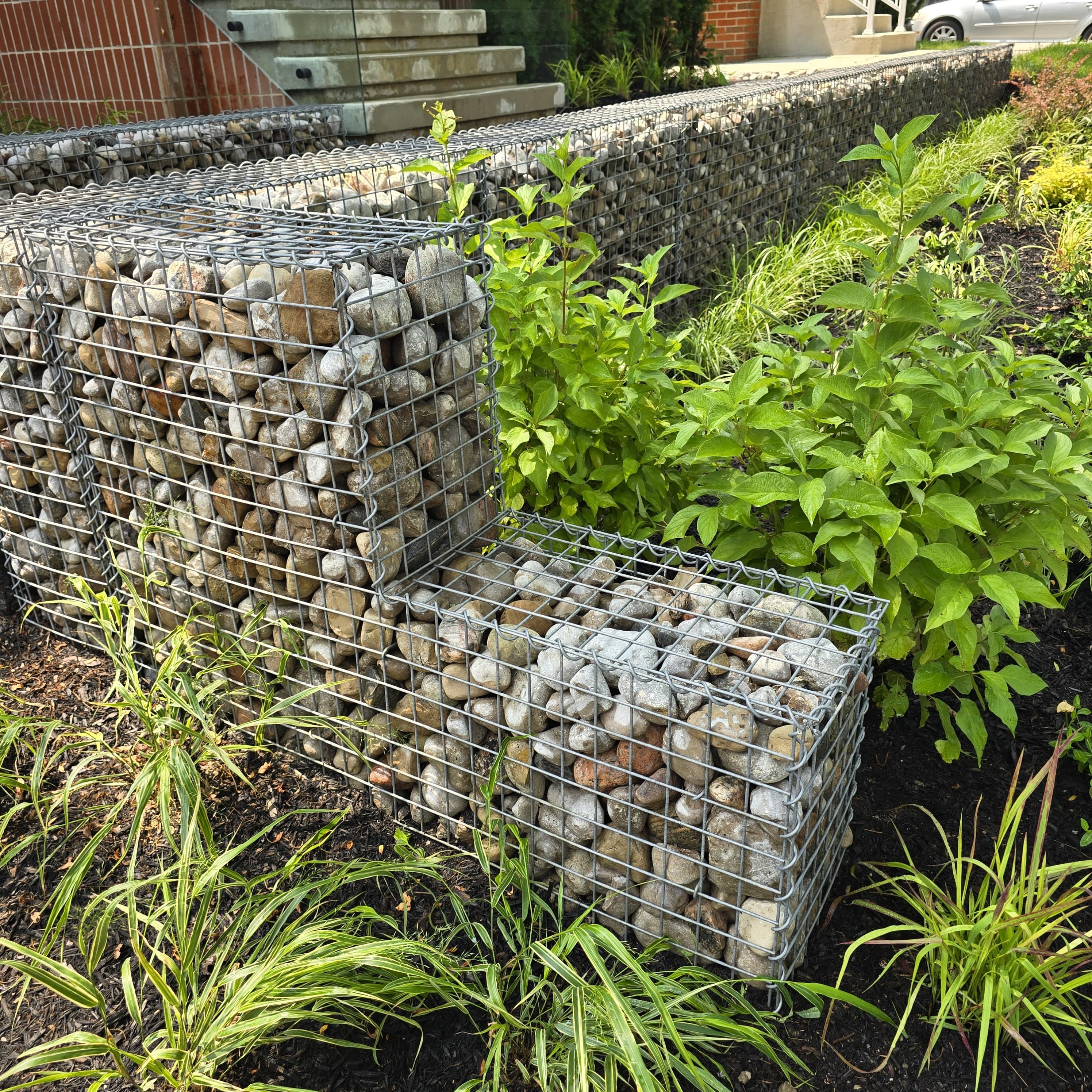 Custom gabion retaining wall with river stone by Cavemen Landscapes in Toronto